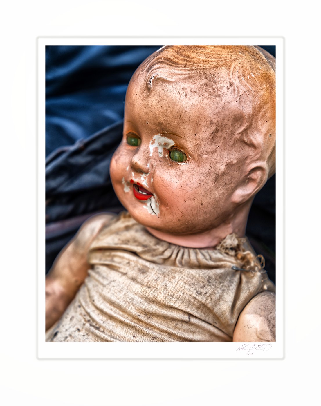 A weathered antique doll with cracked, peeling paint and haunting green eyes.