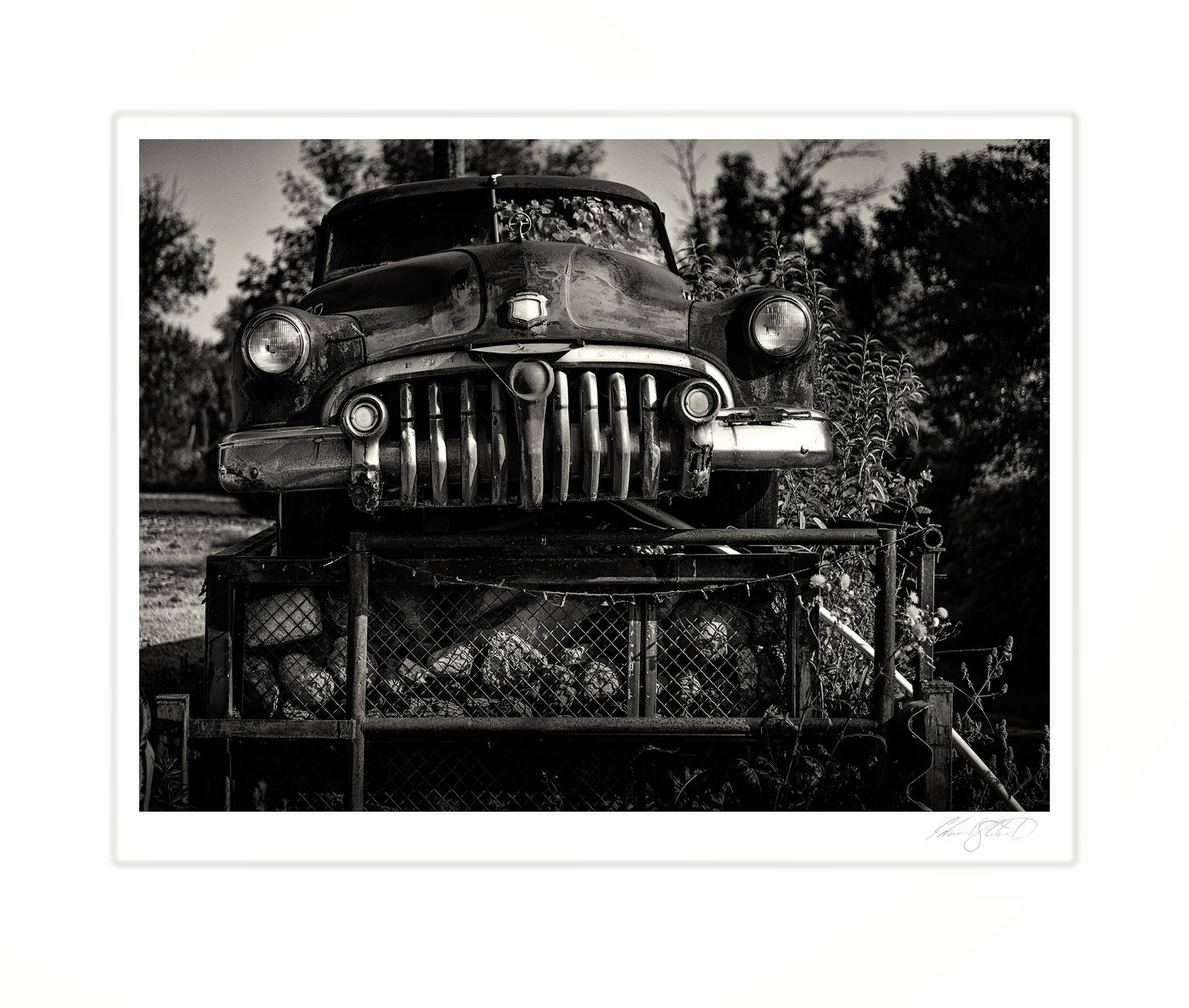 A close-up of a vintage car's grille and headlights in black and white.