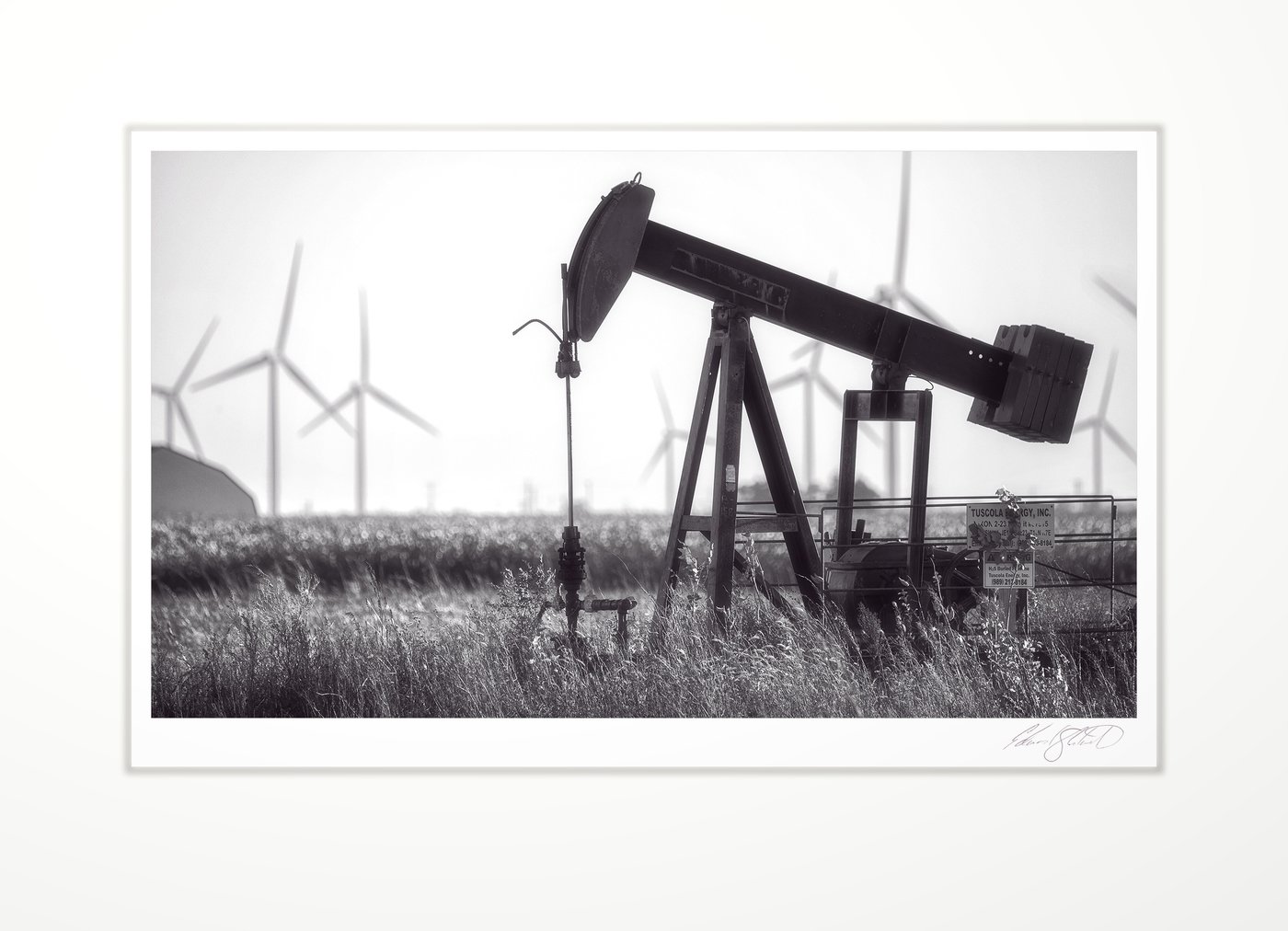 Oil pumpjack with wind turbines behind
