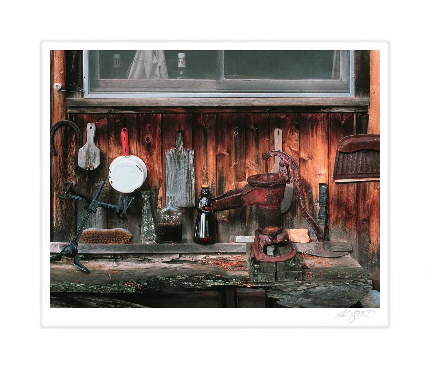 A rustic cabin porch with an old hand pump and antique bottles