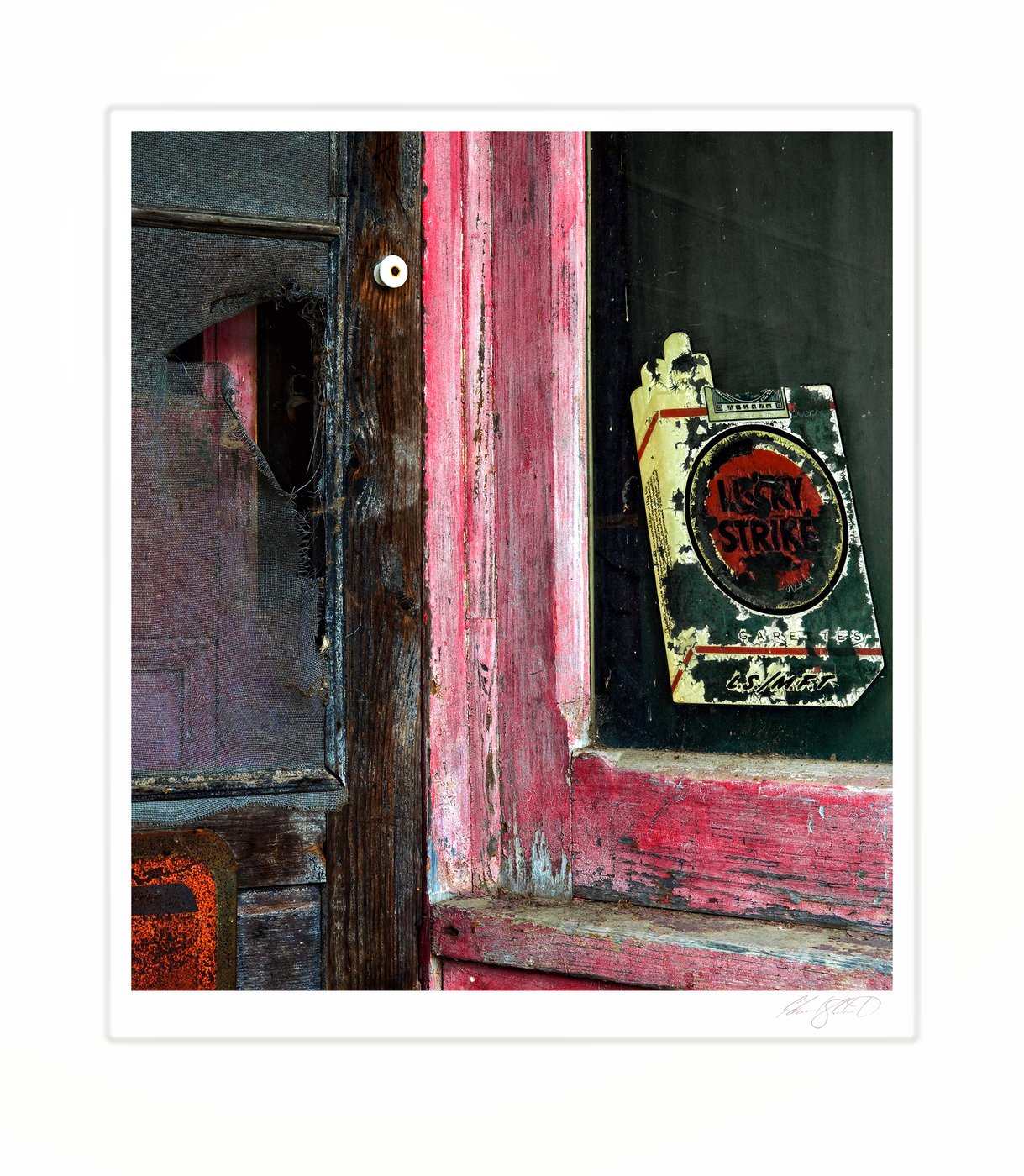 A weathered screen door and peeling Lucky Strike sign at an old gas station