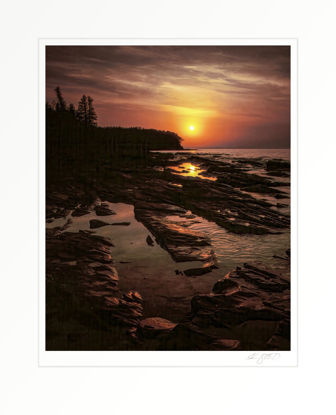 Sunrise over Lake Superior's rocky shoreline with tide pools catching the golden light