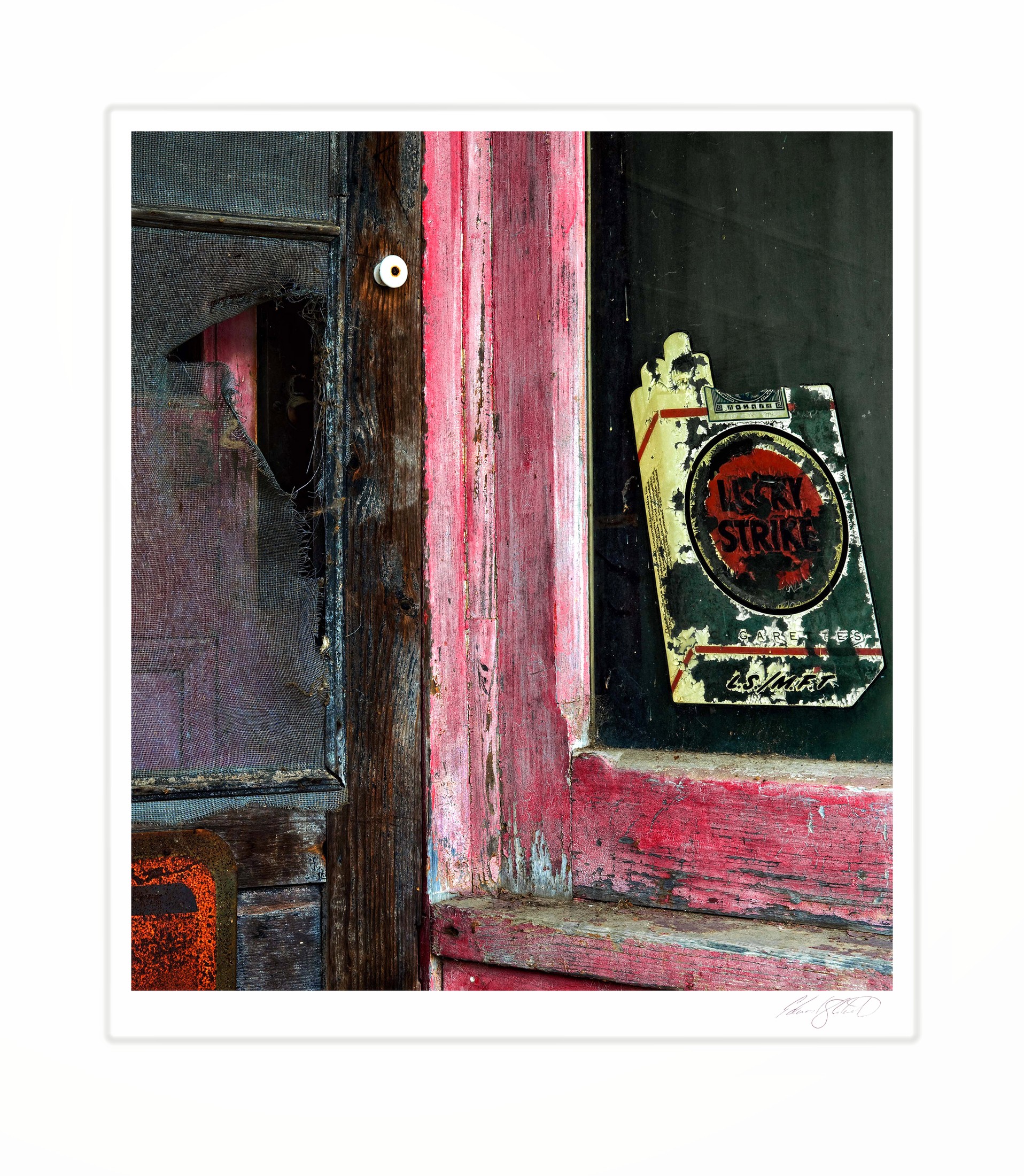 A weathered screen door and peeling Lucky Strike sign at an old gas station