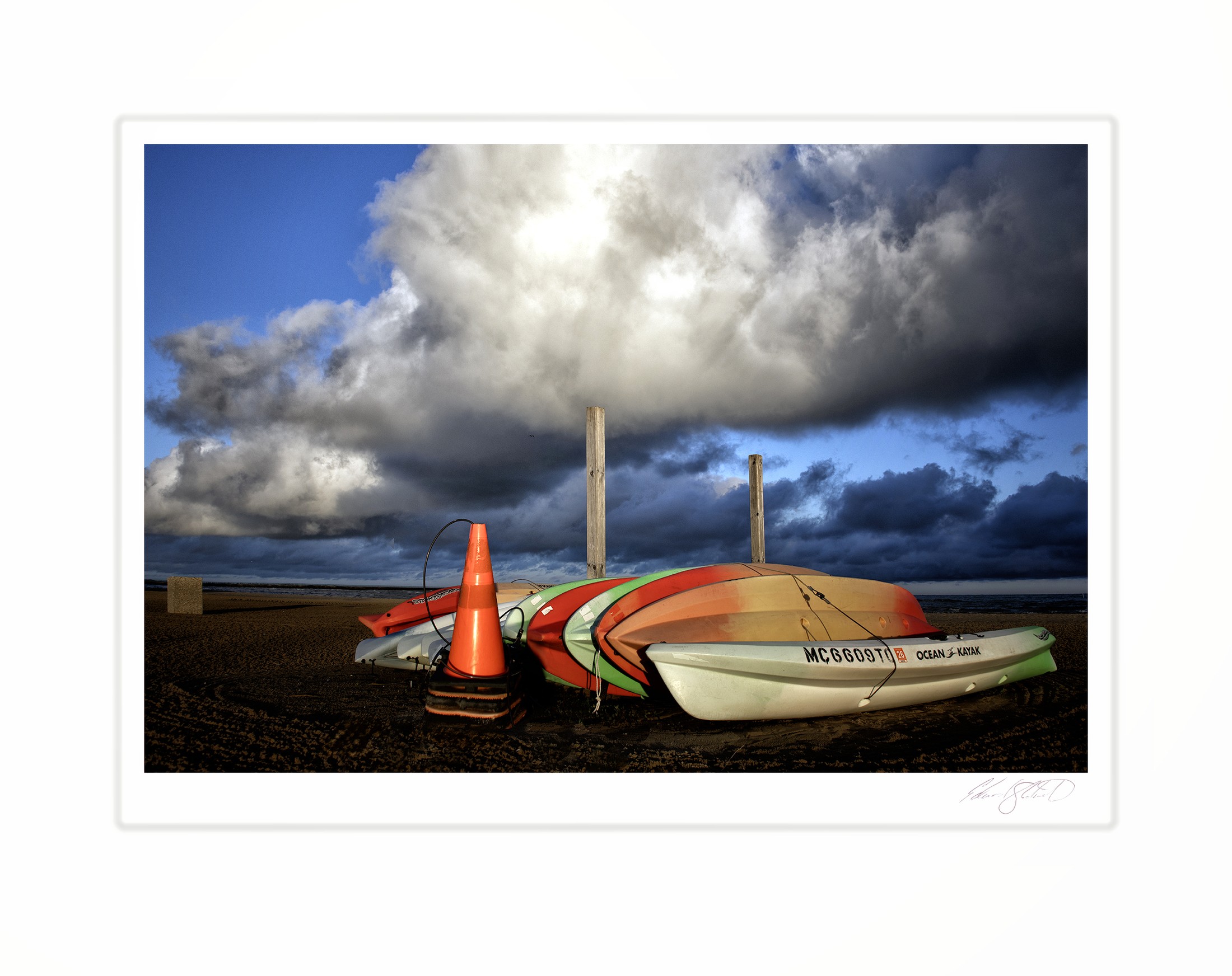 A row of kayaks on the beach beneath a towering storm cloud