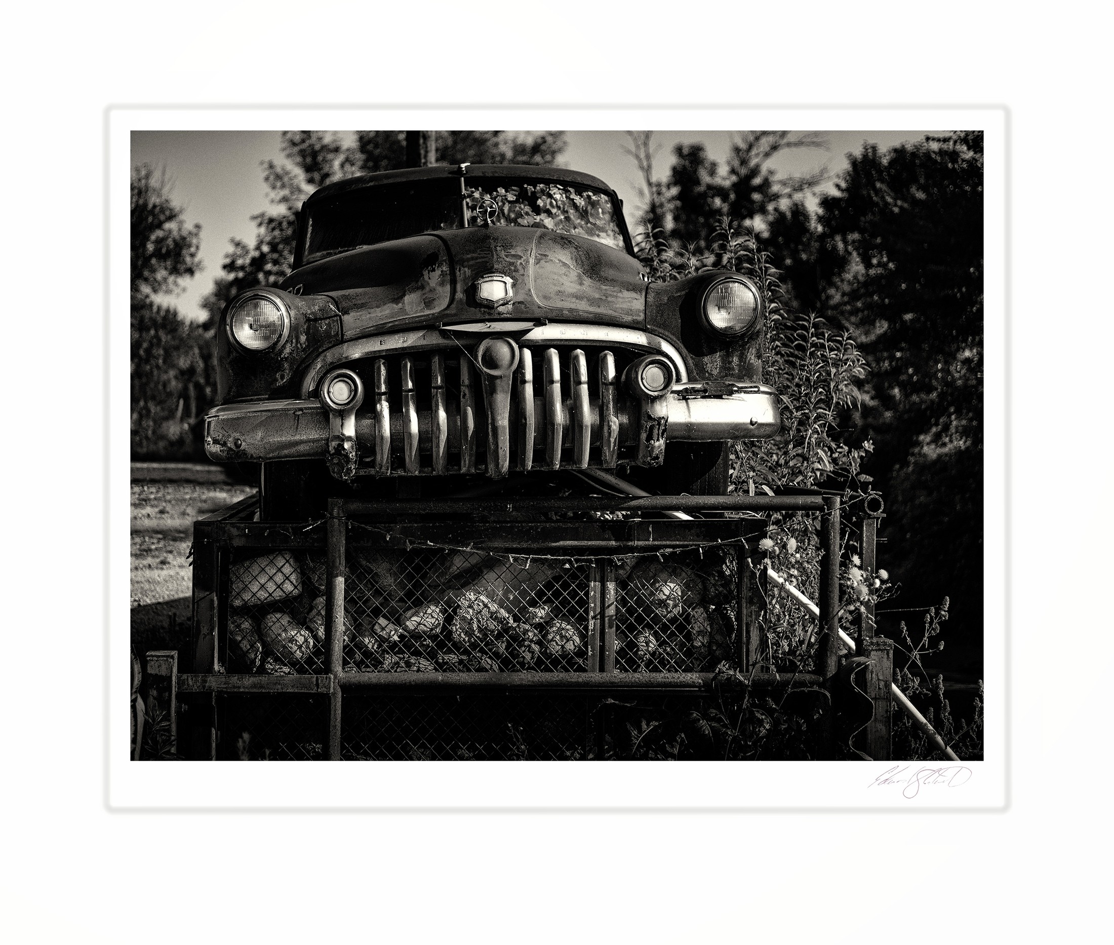 A close-up of a vintage car's grille and headlights in black and white.