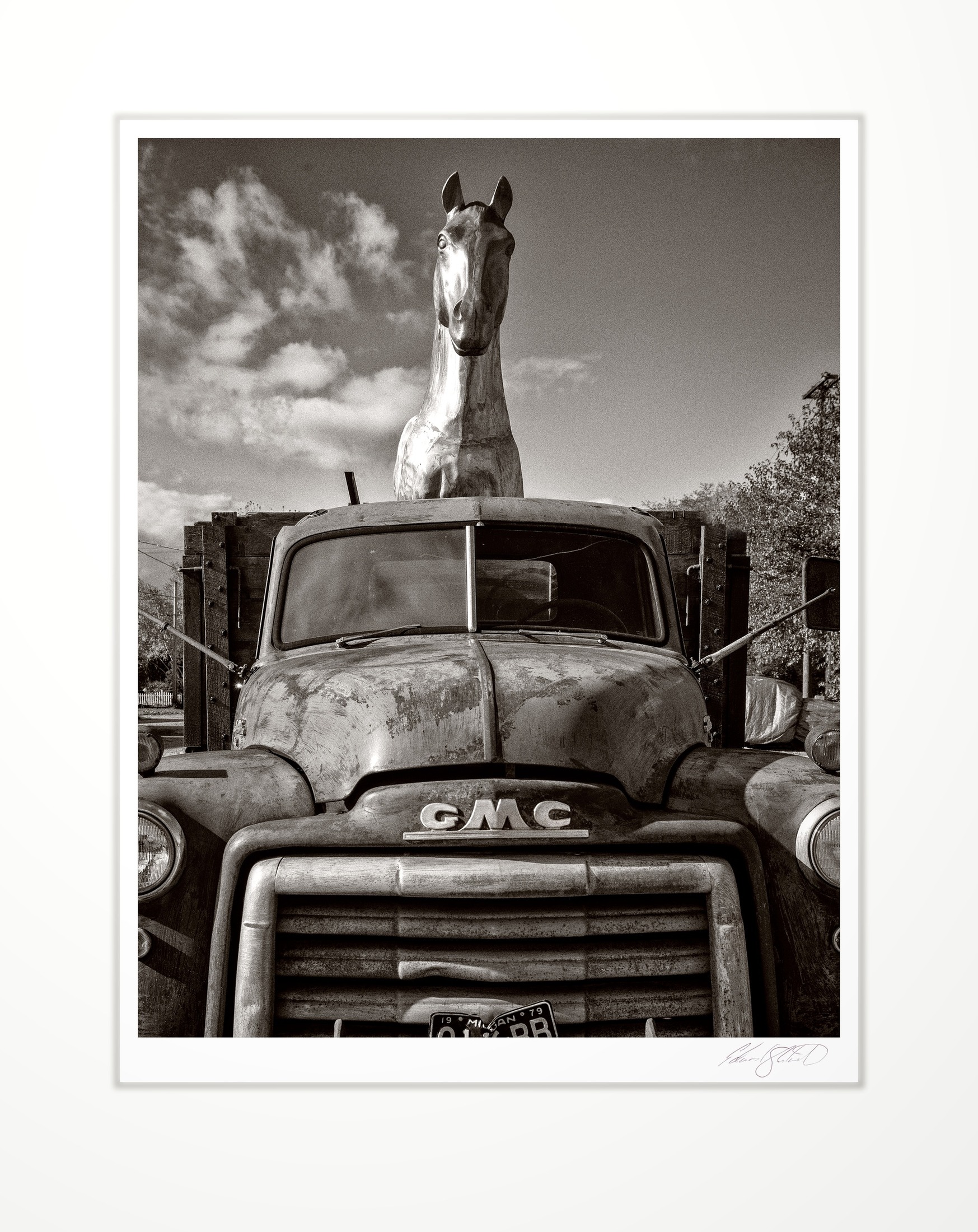 A vintage GMC truck with a horse figure mounted above