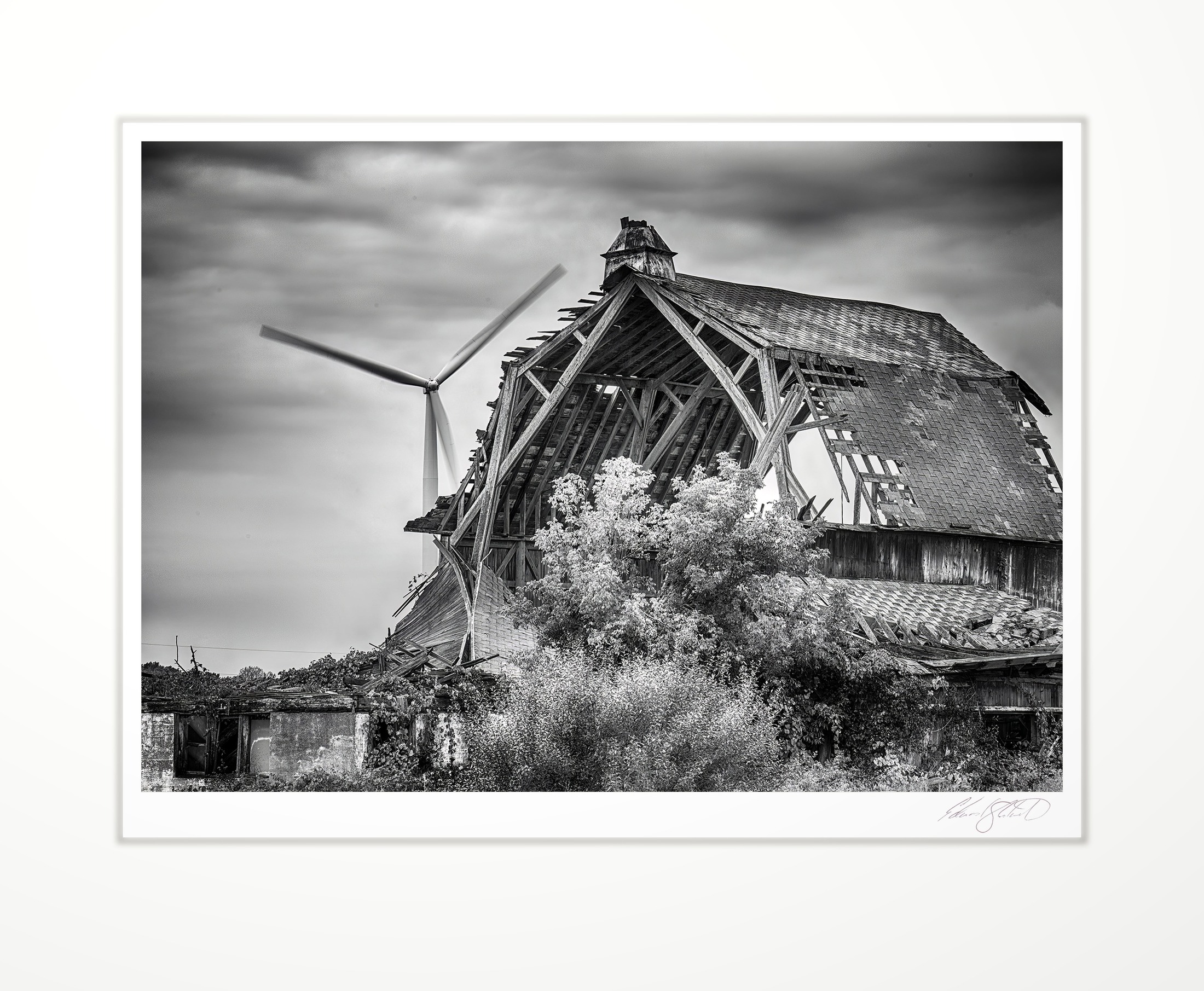 A collapsing barn with a wind turbine turning behind it